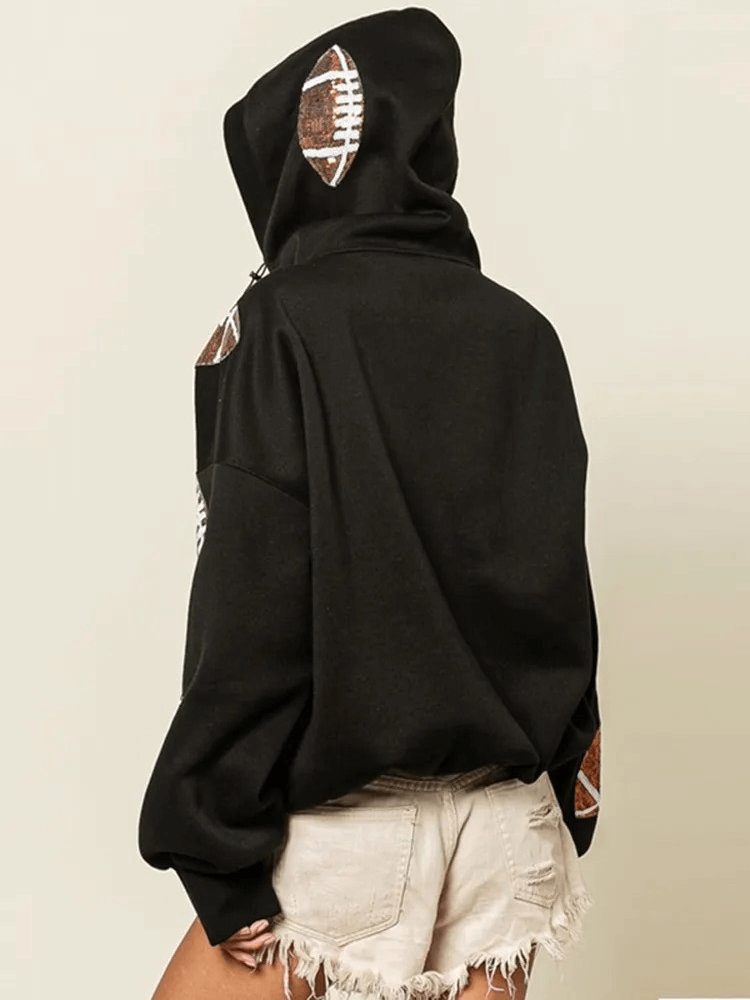 Back view of a woman wearing a sporty casual women's hoodie with football patch decorations, paired with frayed shorts.